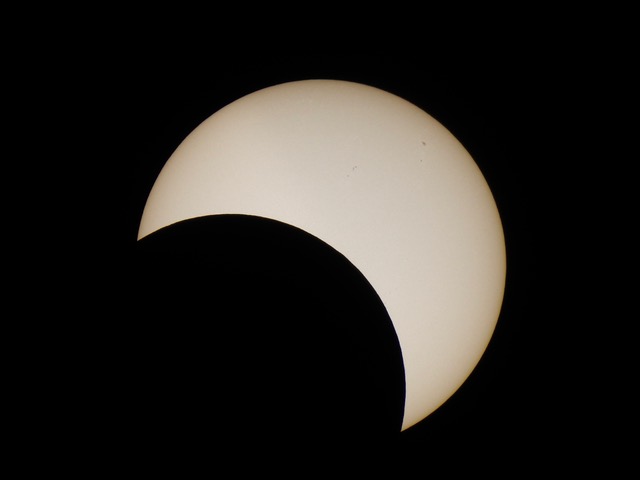Partial solar eclipse with moon covering part of the sun from the bottom left.