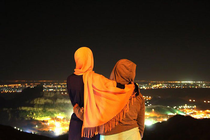 Two women looking over the night landscape of Al Ain