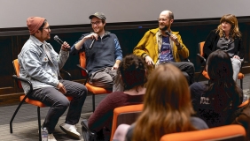 Four filmmakers sit on stage in a panel with microphones