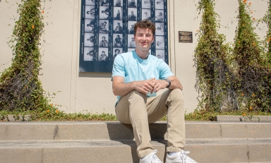 James Steinberger '25 sits on the steps in front of Haines Hall with a blue shirt.
