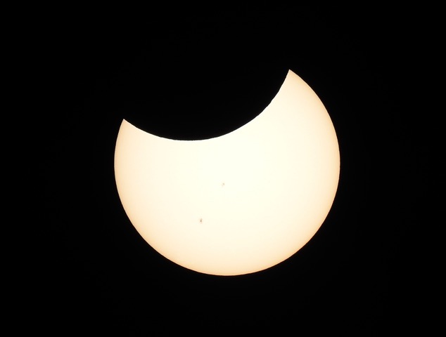 Partial solar eclipse with moon eclipsing the top part of the sun.