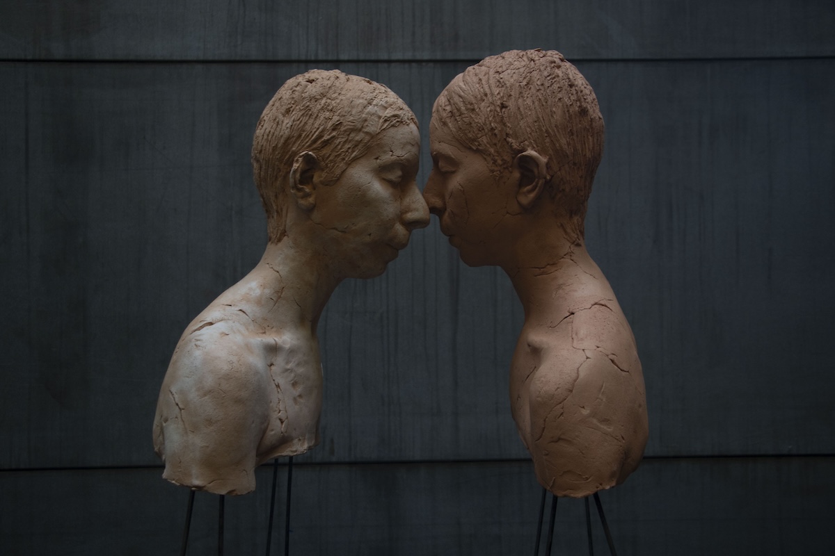 color image of two sculptural busts in profile, with faces touching