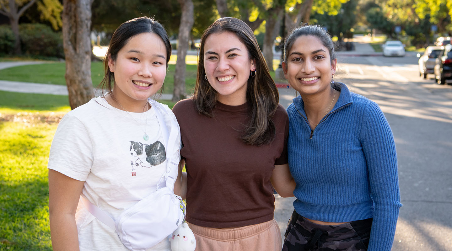Three female Occidental College students standing together and smiling