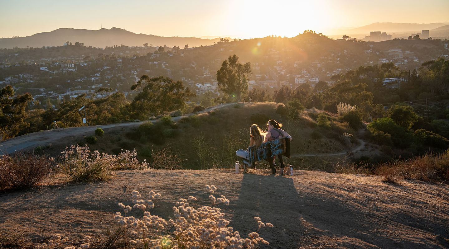 A beautiful sunset on Fiji Hill on campus watched by two students on a bench