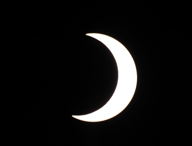 Partial solar eclipse with moon covering the majority of the sun from the left.