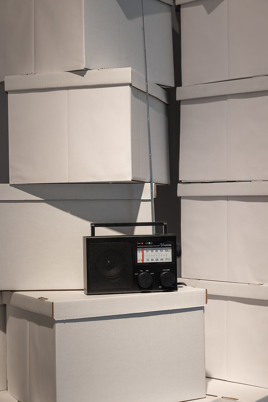 A black radio sits on top of white archival boxes.