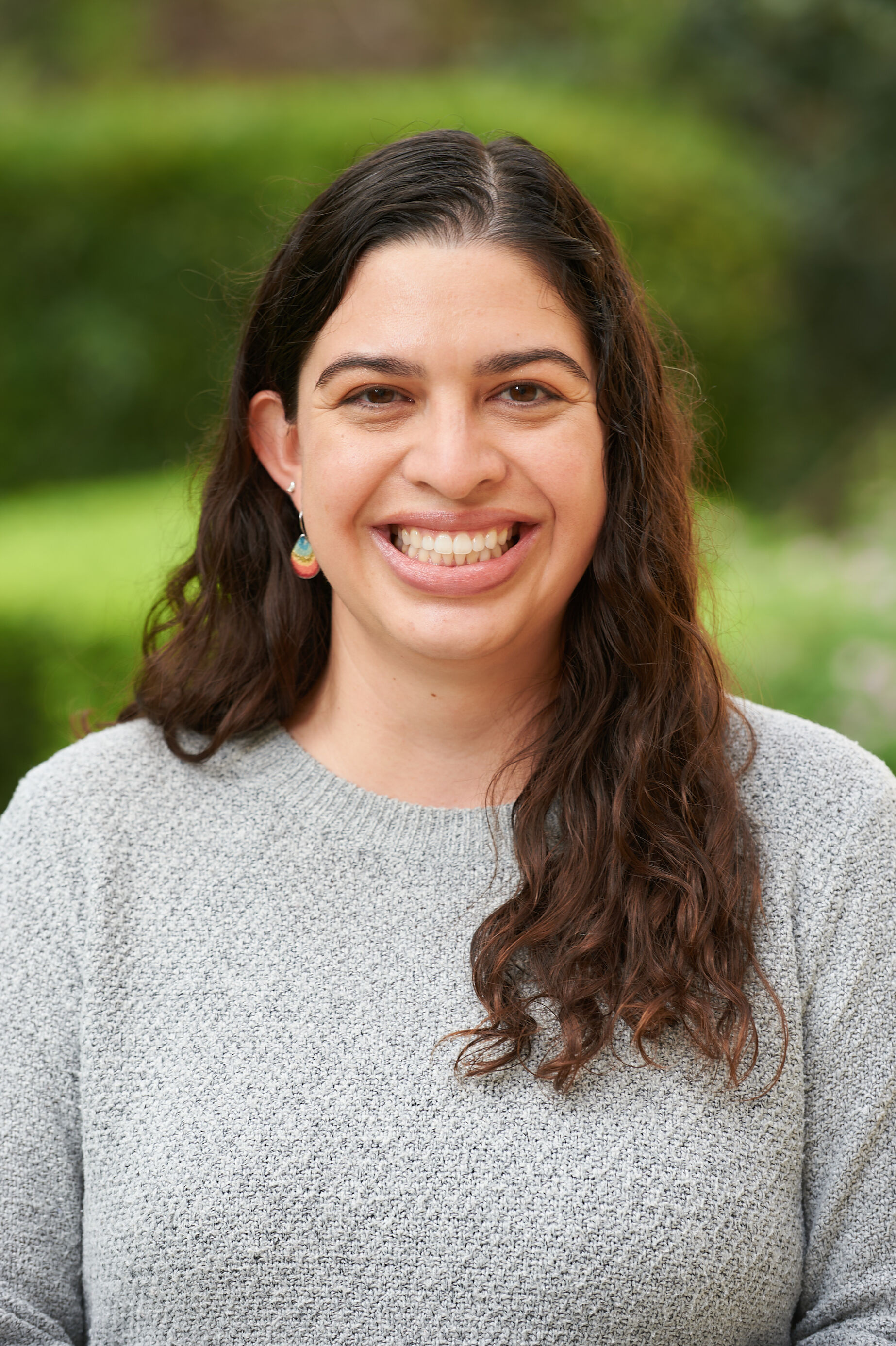 Woman in gray sweater in front of green background