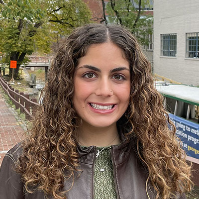 Ava Arabshahi headshot curly brown hair and leather jacket