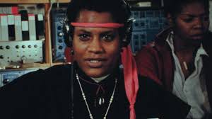 Grainy photo of a person looking straight into the camera wearing a red headband. 