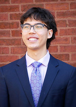 a young man with glasses and a suitcoat and tie, smiling