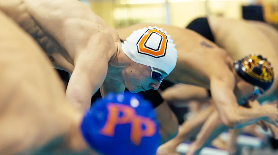 Occidental College swimmer Connor Grant, center, preparing to dive into the pool