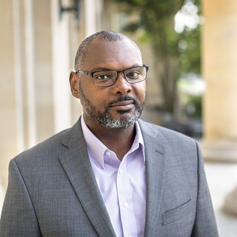 Professor and author Derrick Spires headshot wearing a grey sports coat and glasses