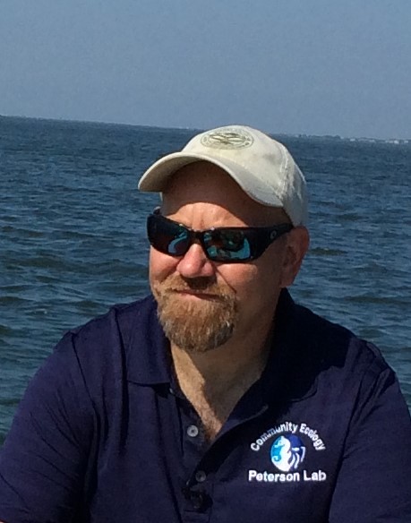 Man with hat and sunglasses in front of water