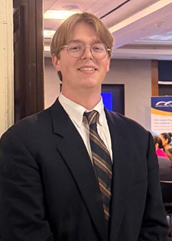 Evan Jensen headshot with black blazer and tie