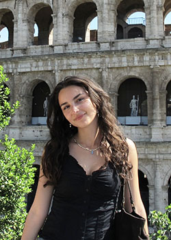 a young woman in a black top standing in front of the Coliseum in Rome