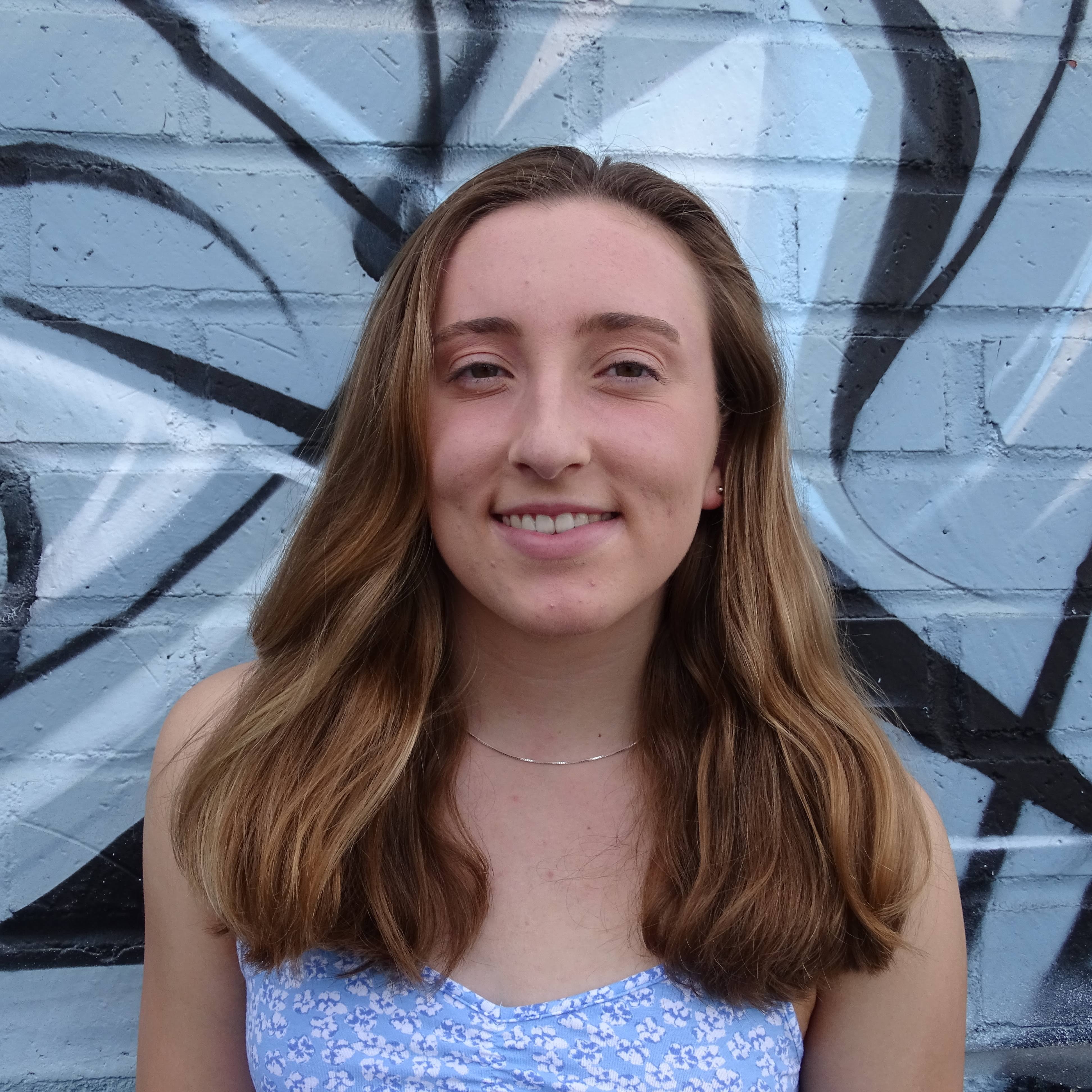 brenna knapp in front of a painted brick wall