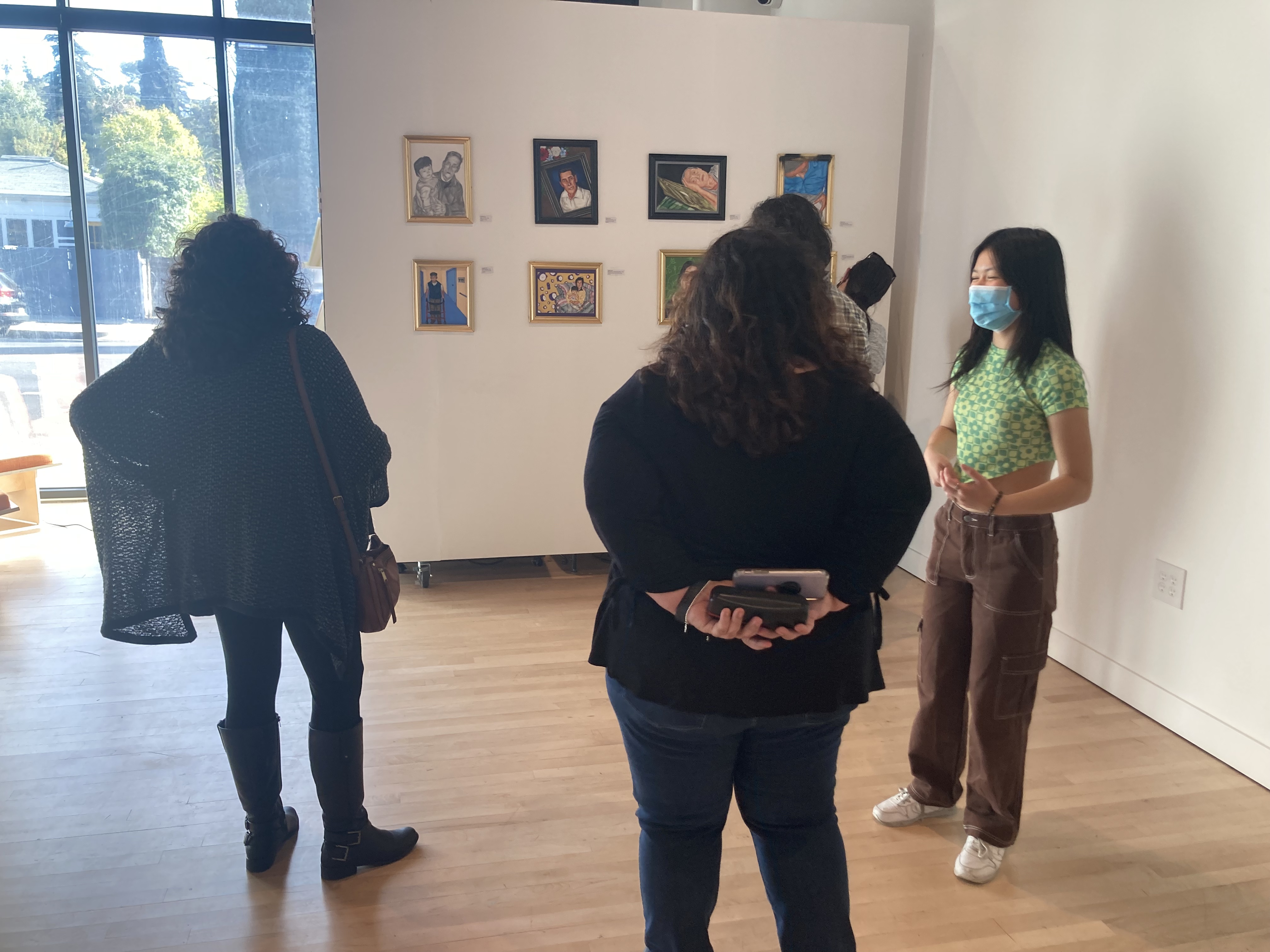 IMG_3383.jpg Photo of three people standing in an art gallery looking at paintings hung on the wall, their backs are turned away from the camera.
