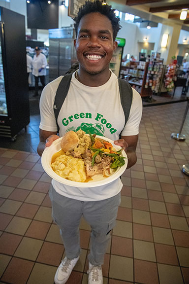 A student holding up a plate of food in the Marketplace