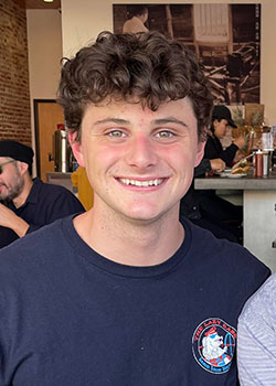 Matthew Spruance headshot navy tshirt smiling