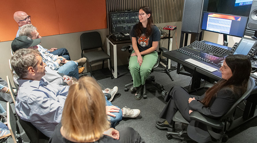 An Occidental music production student in a classroom with music industry professionals, talking