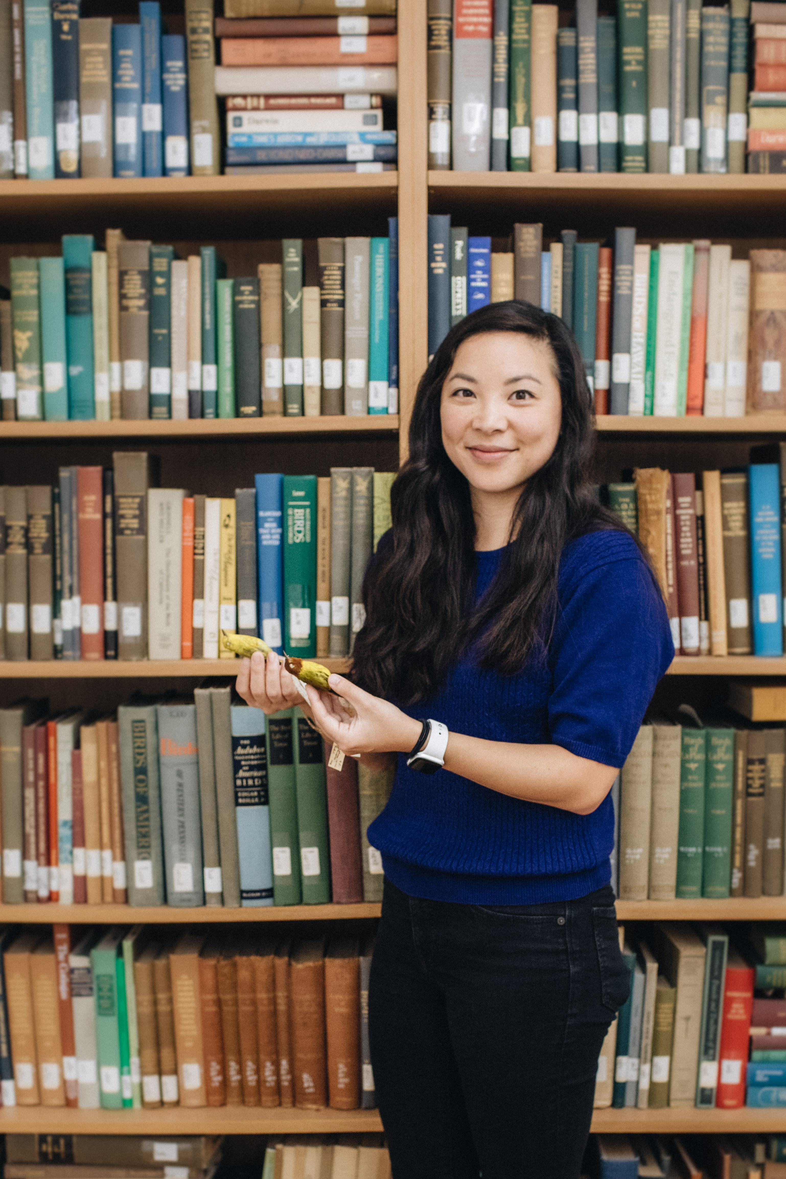 Whitney Tsai Nakashima in front of bookshelf holding birds