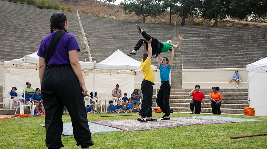 Members of Occidental Children's Theater perform on the grass in brightly colored tshirts