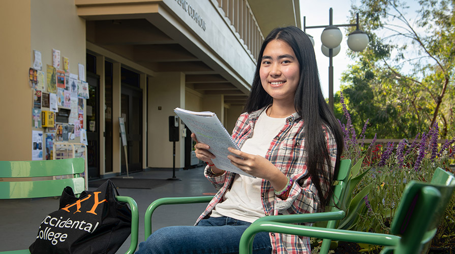 Thina Ly sits at a table on the patio of Academic Commons on campus