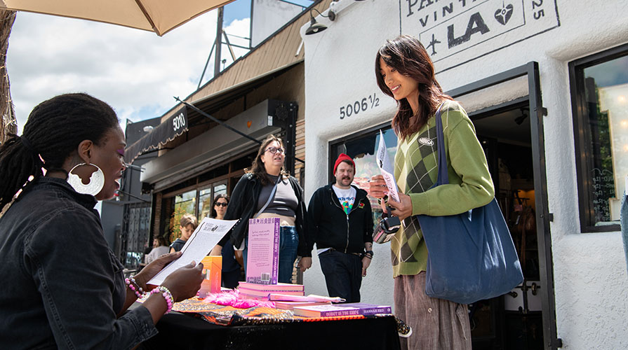 Occidental student Qingxi Yang '28 talks to one of the artists at the art street fair she helped create on York Blvd
