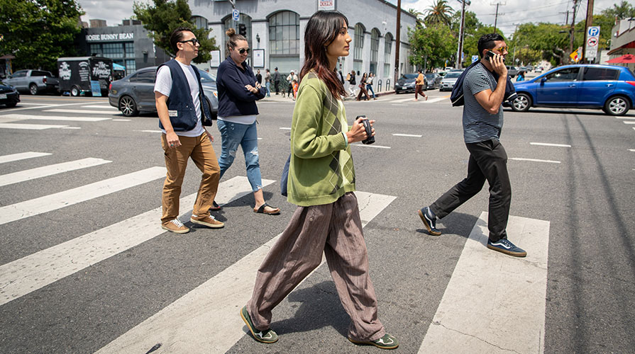 Occidental student Qingxi Yang '28 walks down York Blvd with a video camera in her hand