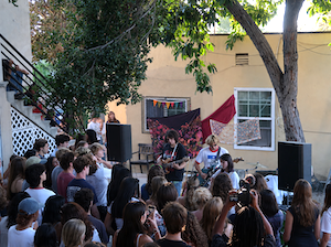 Occidental students at a house party watching fellow students sing and play instruments.