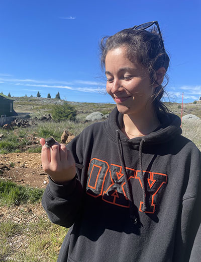 Alana Pizarro holding a tiny specimen with a grey Oxy hoodie on