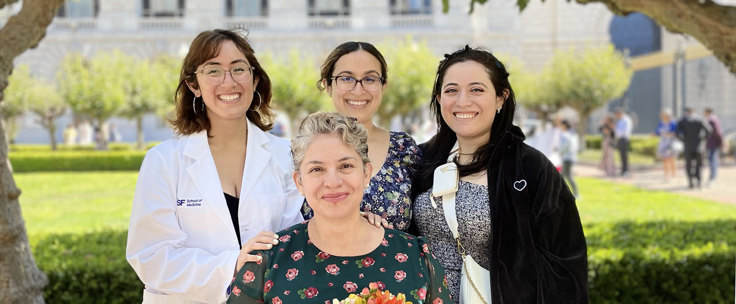 Oxy alumna in her white lab coat and her colleagues posing on a lawn