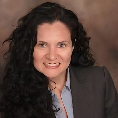 Priscilla is smiling and is wearing a blue shirt with a black jacket