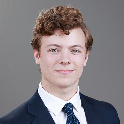 Tommy Quick headshot in business suit, red hair
