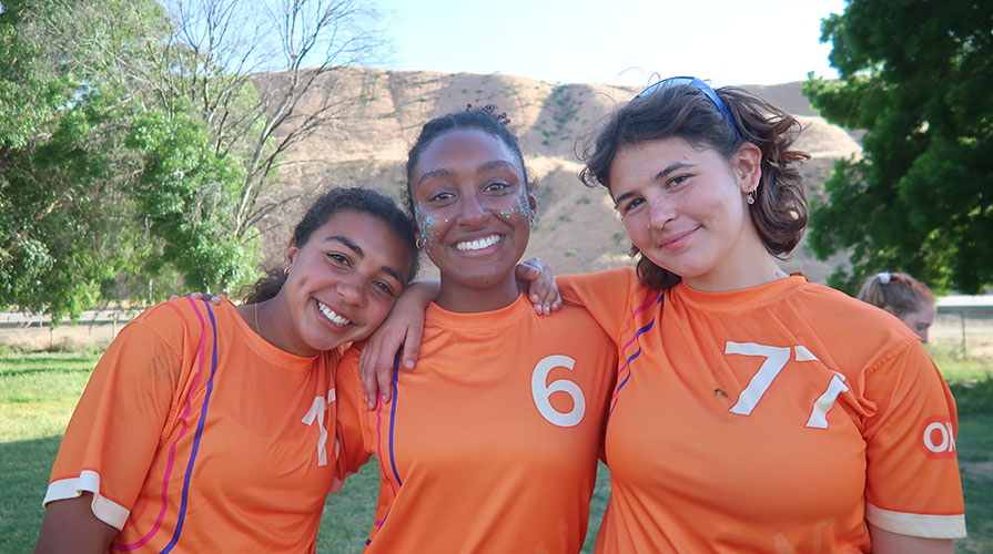 Three female Occidental students with ultimate frisbee jerseys, standing together