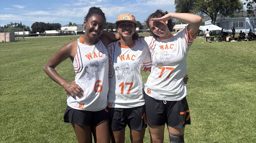 Occidental College students from the women's ultimate frisbee team pose together on the field
