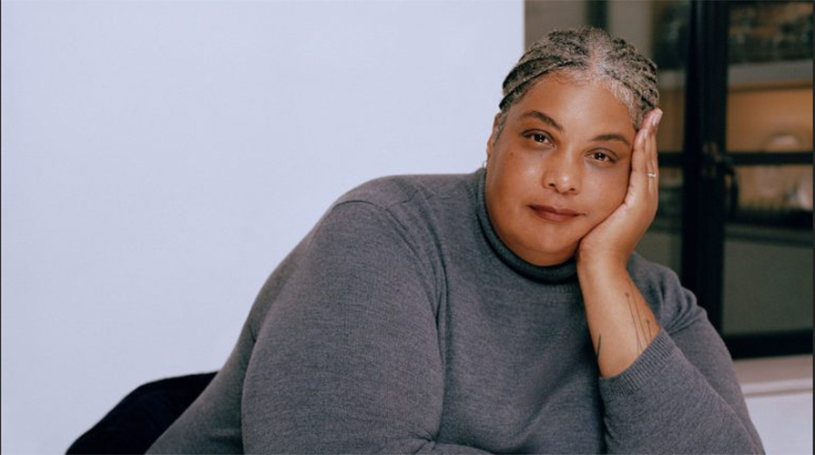 Roxane Gay in a grey sweater leaning her face on her hand