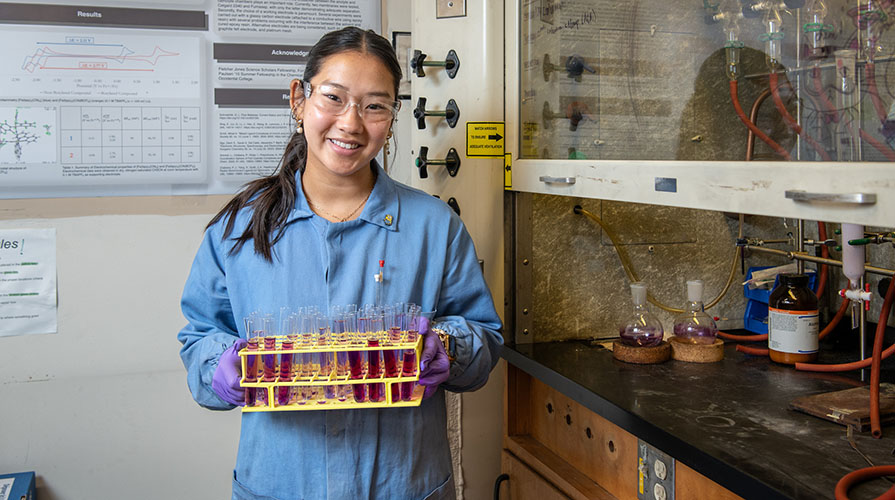 Kaylee Nguyen in the chemistry lab holding a set of test tubes and smiling