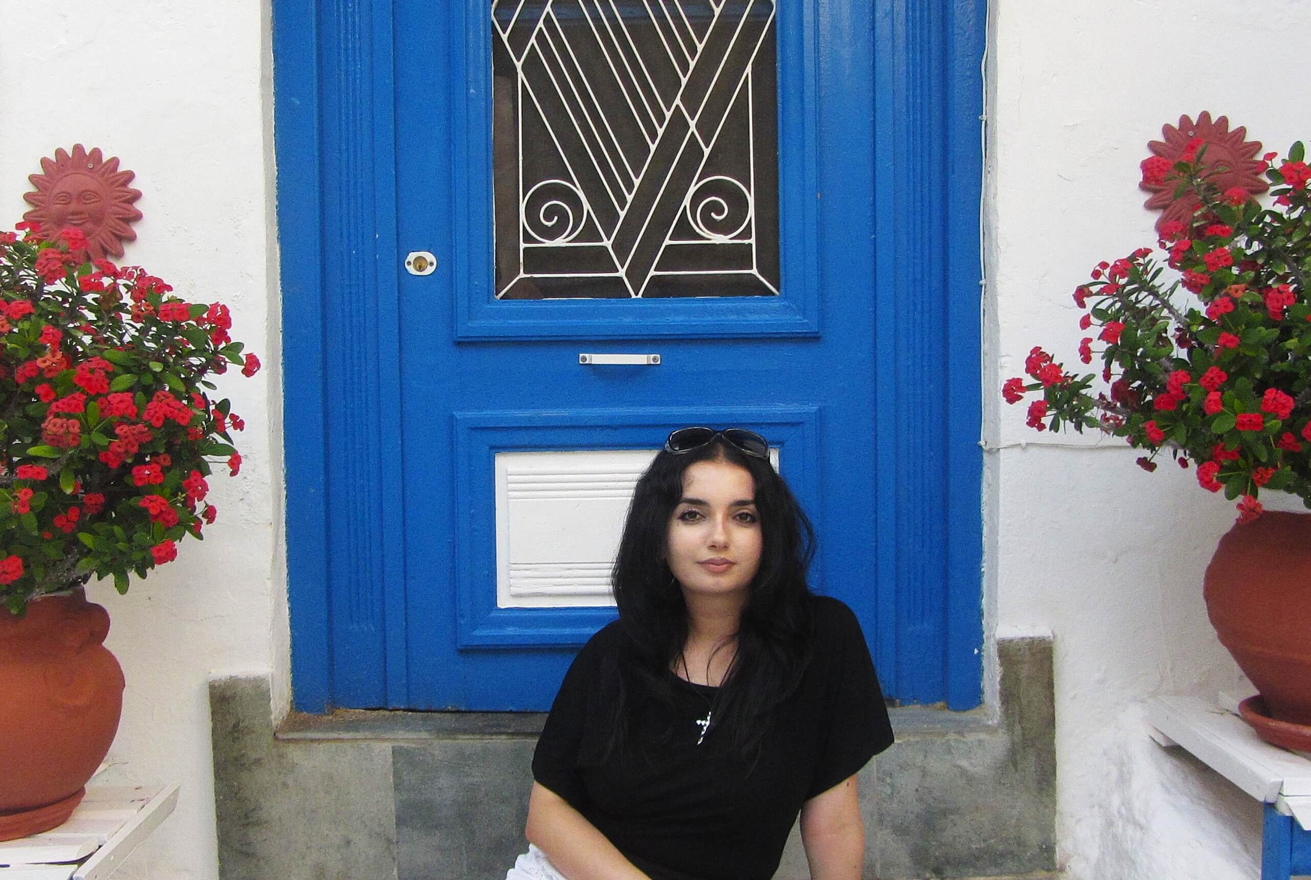 Serine_Peer Tutor in Russian in front of a blue door in Greece