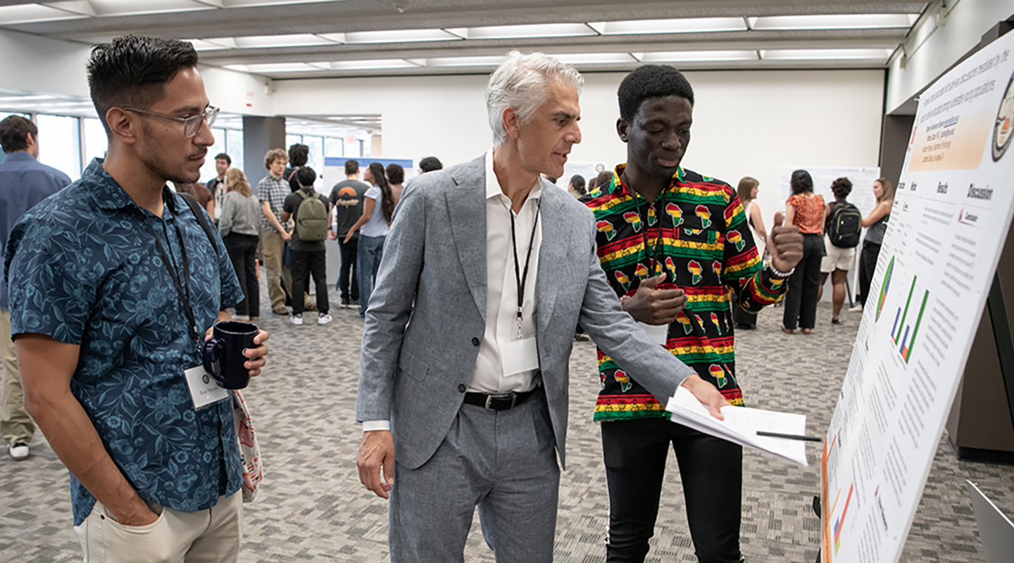 Assistant Professor of Chemistry Raul Navarro and President Stritikus discuss cognitive science major Stephen Sekyere '28's research at Occidental's Summer Research Program Conference on July 30.