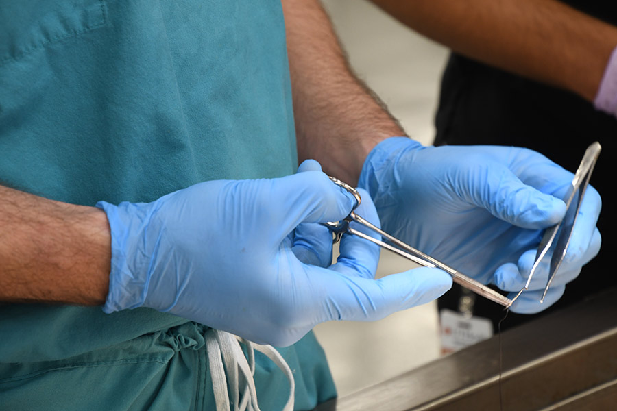 a medical student handling scissors and suture material