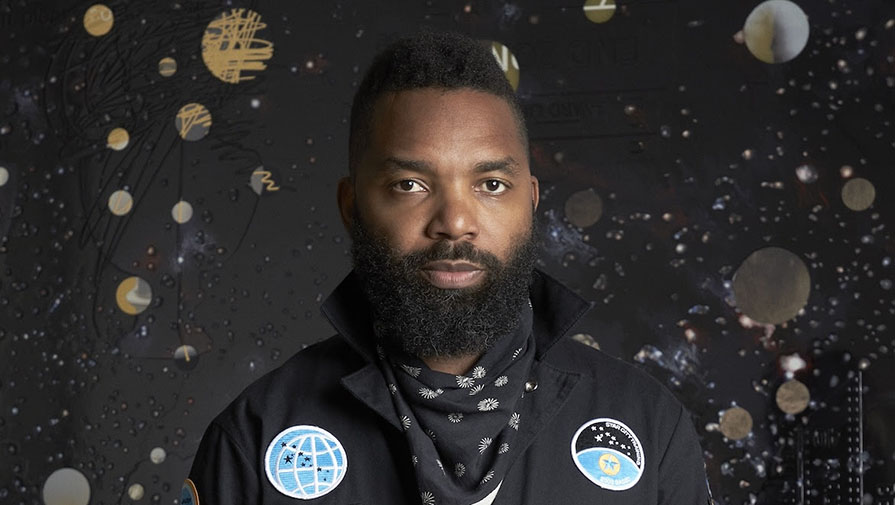 Tavares-Strachan_895x500_0.jpg Man in black space suit with black background