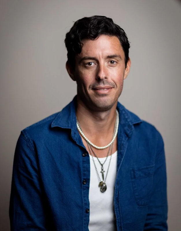 podcaster Tim Miller in a blue shirt with short dark hair looking at the camera