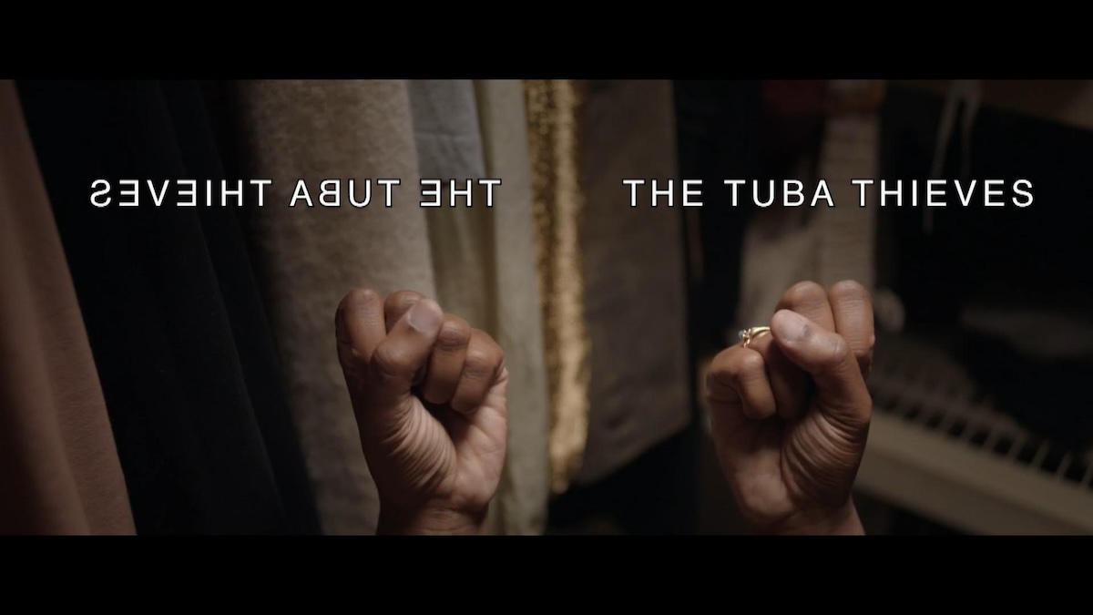screen capture image from the film THE TUBA THIEVES featuring a mirror image of a hand signing ASL, with open captions