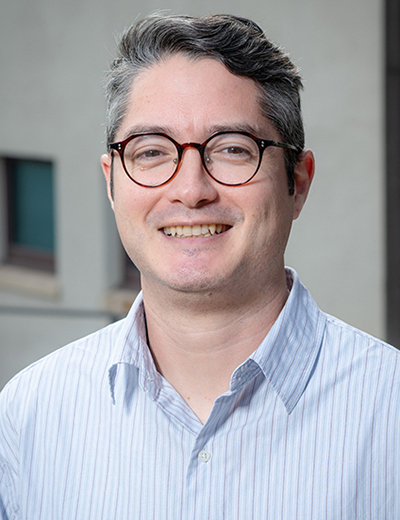 Joel Walsh headshot with collared shirt and glasses