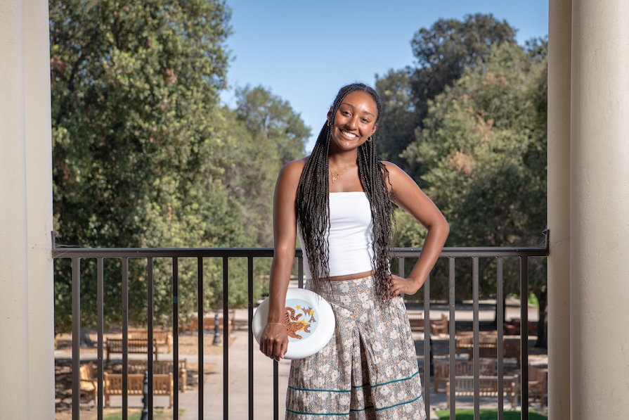 Occidental Student posing for photo on the Los Angeles Campus holding a Frisbee overlooking the Quad