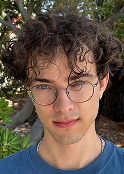 William is wearing a blue shirt and glasses