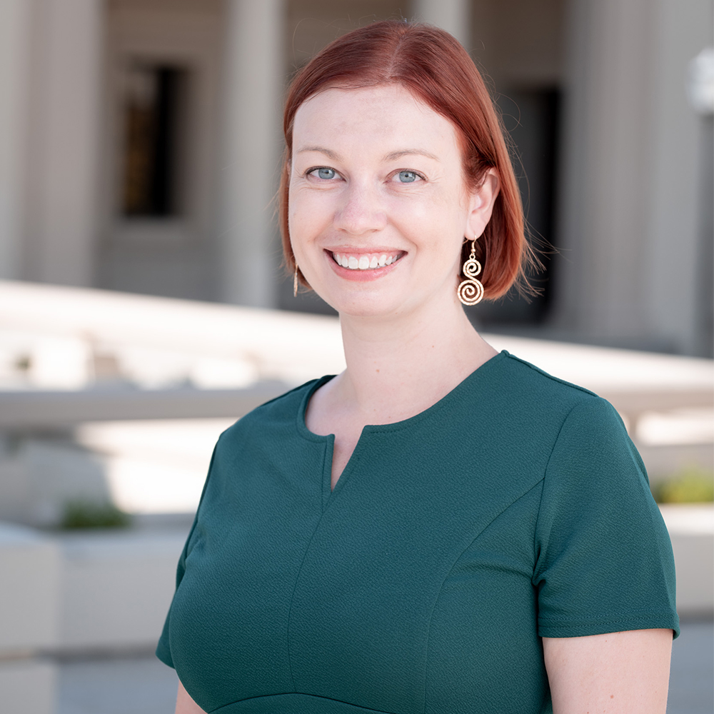 a smiling redheaded woman in a teal green top