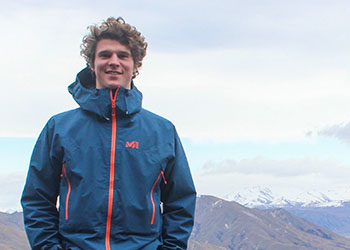 A head shot of Occidental college student Sam Sachs against a mountain range 