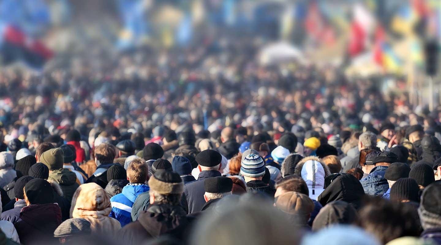 rear view of a large crowd of people viewing international flags
